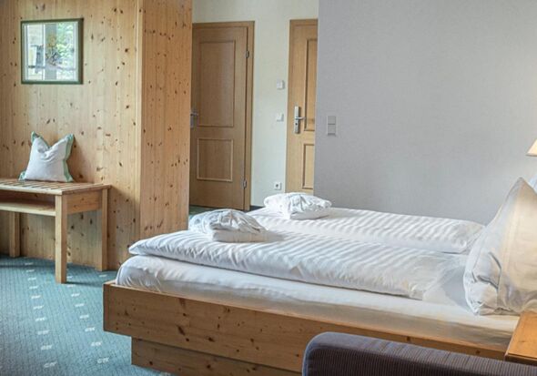 Das Doppelbett des Sonnberg Doppelzimmers Classic, mit Blick auf die neu getafelte Holzwand