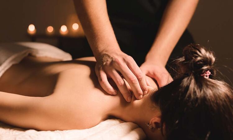 Eine Frau genießt die Nackenmassage auf einer Liege und entspannt bei einer wohltuenden Wellness-Behandlung in einem Hotel im Salzkammergut