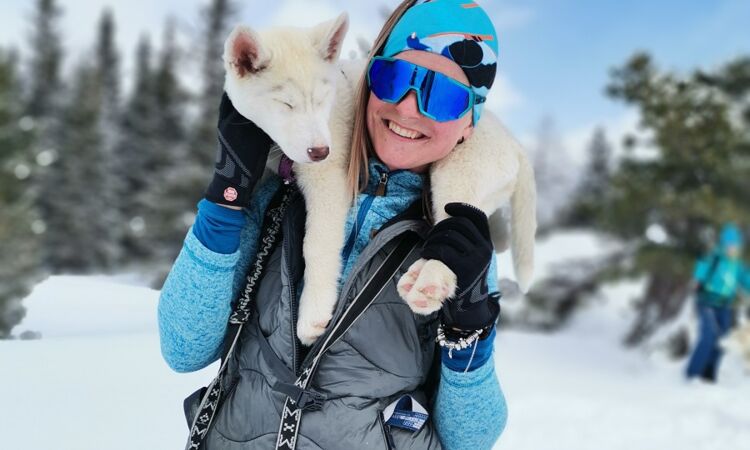 A woman with a husky on her shoulder.