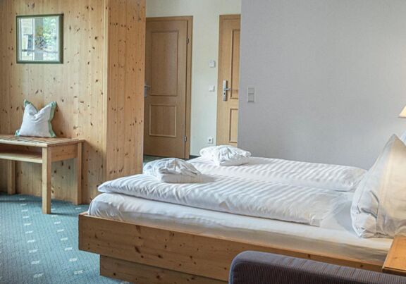 Das Doppelbett des Sonnberg Doppelzimmers Classic, mit Blick auf die neu getafelte Holzwand