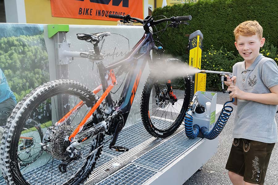 Young person washes his bike on holiday at the hotel bike wash in Hintersee in the Salzkammergut region of Austria
